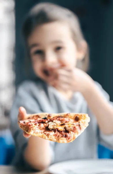 Porträt eines kleinen Mädchens mit einem appetitlichen Stück Pizza. — Stockfoto