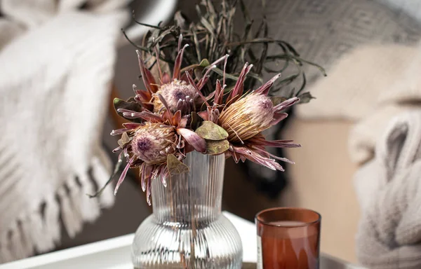 Composición casera con un ramo de flores de protea y velas. — Foto de Stock