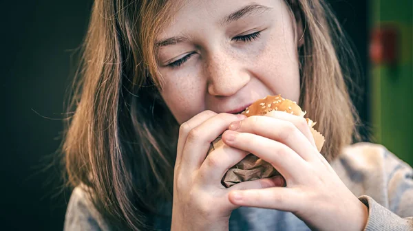 주근깨가 있는 어린 소녀가 햄버거를 먹는다. — 스톡 사진