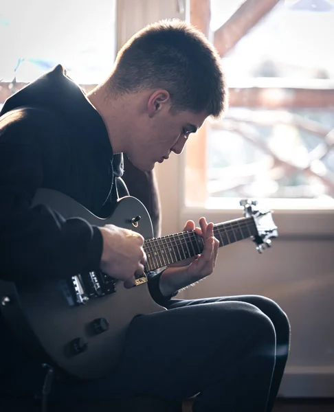 Un jeune homme joue de la guitare électrique dans sa chambre. — Photo