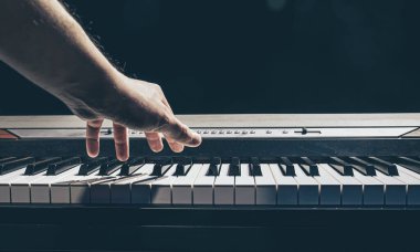 Erkek eller karanlıkta piyano tuşlarını çalar..