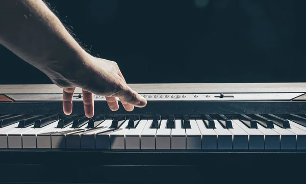 Manliga händer spelar piano tangenterna i mörkret. — Stockfoto