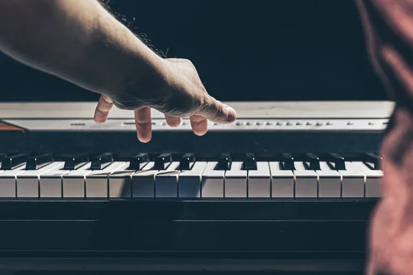 Manliga händer spelar piano tangenterna i mörkret. — Stockfoto
