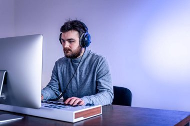 Erkek müzisyen bilgisayar ve klavye, müzisyen işyeri kullanarak müzik yaratır.