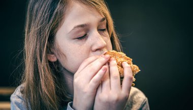 Çilli küçük bir kız hamburger yiyor..