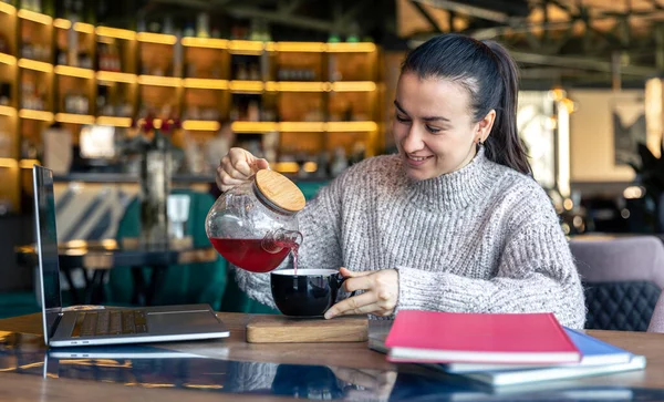 Mujer de negocios en un café con un portátil bebe té. — Foto de Stock