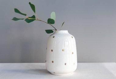 Açık arkaplanda puantiyeli dekoratif beyaz vazo..