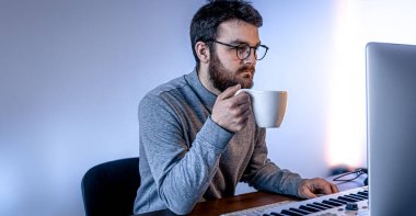 Erkek müzisyen bilgisayar ve klavye, müzisyen işyeri kullanarak müzik yaratır.