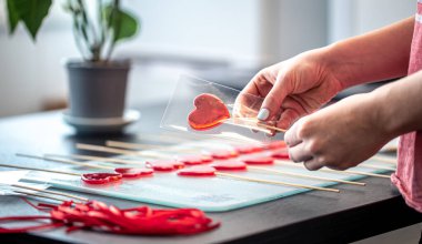 Kalp şeklinde kırmızı lolipoplar paketleme.