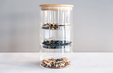 Aydınlık arka planda cam kavanozlardaki farklı çay türleri, izole edilmiş..