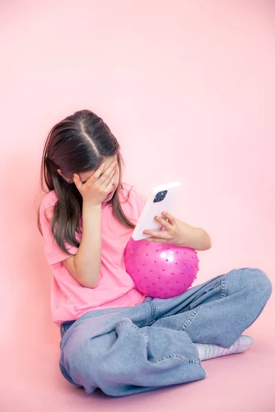 Kleines Mädchen mit Smartphone in der Hand auf rosa Hintergrund, Kopierraum. — Stockfoto