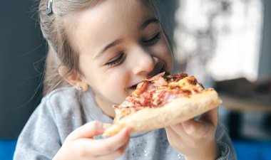 İştah açıcı bir dilim pizzayla küçük bir kızın portresi..