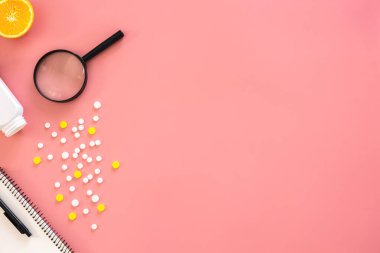Pembe arka planda düz yatak, haplar ve büyüteç, kopyalama alanı.