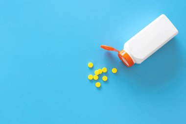 Haplar mavi arka plandaki bir kavanozdan dökülür..