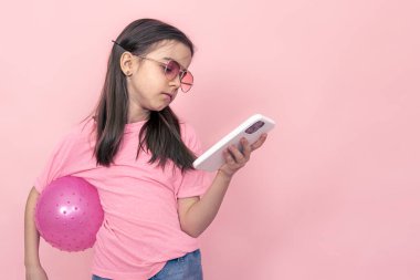 Pembe arka planda akıllı telefonu olan şık küçük bir kız..