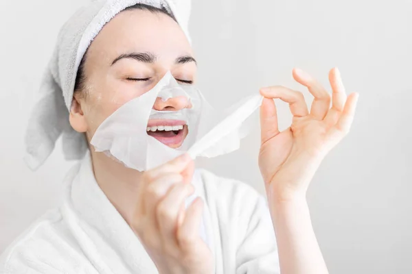 Jovem com máscara de lençol no rosto, procedimento de spa. — Fotografia de Stock