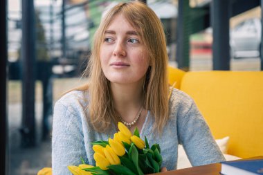 Sarı lalelerle dolu buketi olan güzel genç bir kadın..