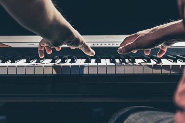 Erkek eller karanlıkta piyano tuşlarını çalar..