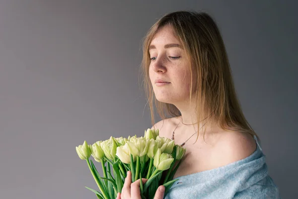 Portré egy fiatal nő egy csokor tulipán egy szürke háttér. — Stock Fotó