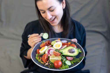 Taze sebzeli iştah açıcı salata ve kadın ellerinde bir tabakta yumurta..