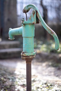 Yarı eski mavi demir su musluğu dışarıda duruyor..