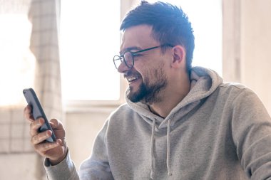 Gözlüklü bir adam akıllı telefon kullanır..