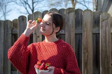 Ahşap arka planda çilek tabağı olan genç bir kadın..