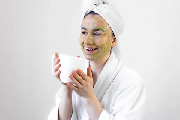 顔とカップの上に緑の美容マスクを持つ若い女性. — ストック写真
