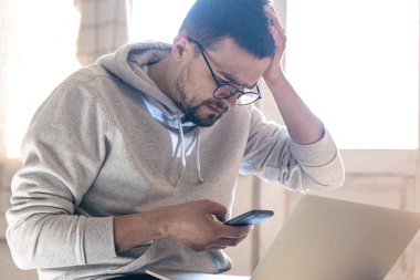 Gözlüklü bir adam dizüstü bilgisayarla çalışıyor..