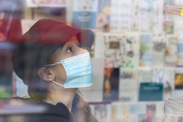Gadis kecil bertopeng medis pelindung di toko buku. — Stok Foto
