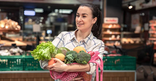 Markette sebze ve meyvelerle alışveriş yapan genç bir kadın.. — Stok fotoğraf