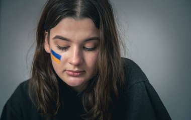 Yüzünde Ukrayna bayrağı olan Ukraynalı bir kız..