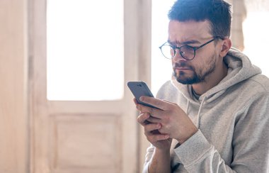 Gözlüklü bir adam akıllı telefon kullanır..