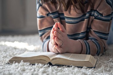 Genç bir kadın yerde yatarken İncil okuyor..