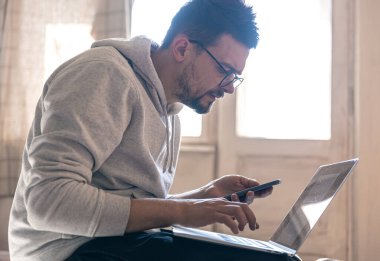 Gözlüklü bir adam dizüstü bilgisayarla çalışıyor..