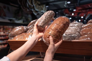 Bir kadın süpermarkette elinde ekmek tutuyor..