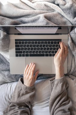 Yatakta yatarken dizüstü bilgisayarda çalışan bir kadın..