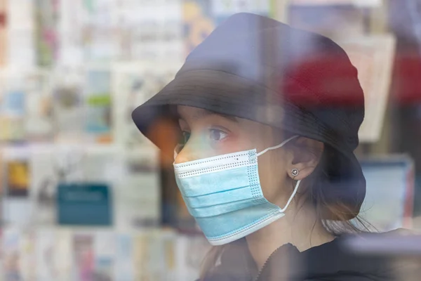 Fetiță într-o mască medicală de protecție într-o librărie. — Fotografie, imagine de stoc