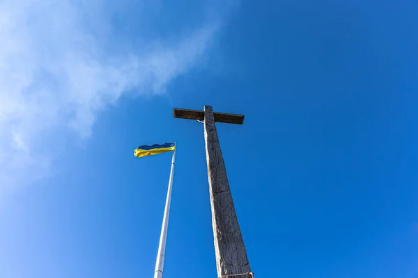 La crucifixión de Jesucristo y la bandera de Ucrania contra el cielo azul. — Foto de Stock