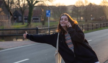 Gün batımında araba bekleyen genç bir kadın..