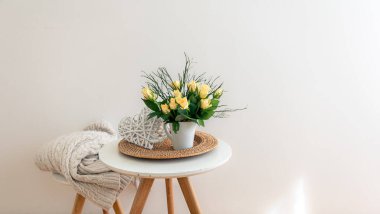 Beyaz bir odanın içindeki vazoda çiçekli ev kompozisyonu.