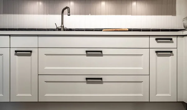 White kitchen cabinets with metal pulls or knobs in home interior.