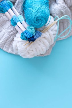 Mavi arkaplanda farklı renk iplikleri, düz yatış, kopyalama alanı.