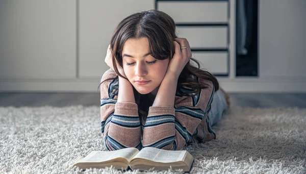 Sevimli genç bir kadın evinde yerde yatarken kitap okuyor, boşluğu kopyalıyor..