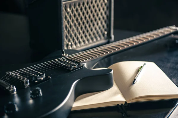 Közelkép, elektromos gitár és jegyzettömb, a zenei kreativitás fogalma. — Stock Fotó
