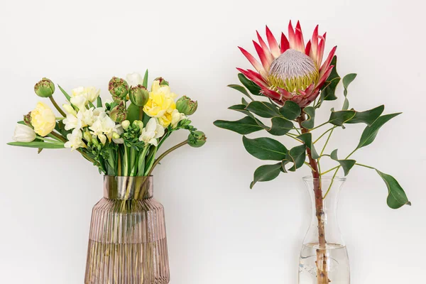 Dos ramos de flores sobre un fondo blanco en jarrones. — Foto de Stock