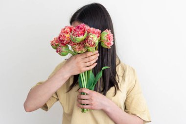 Beyaz arka planda bir buket çiçekle genç bir kadın..