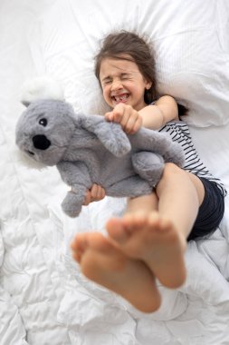 Yatakta yumuşak oyuncak koalası olan mutlu küçük kız..