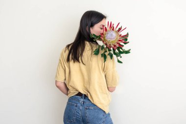 Beyaz arka planda protea çiçeği olan genç bir kadın..