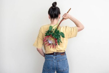 Beyaz arka planda protea çiçeği olan genç bir kadın..